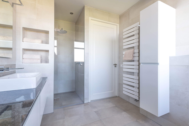 Moderne, stijlvolle badkamer met drempelloze inloopdouche, wandbeugels en antislipvloer, ingericht als veilige badkamer voor ouderen.